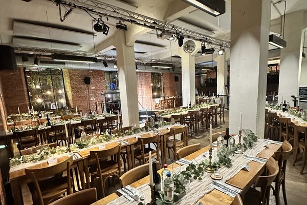 The room set with long tables and a foliage runner.